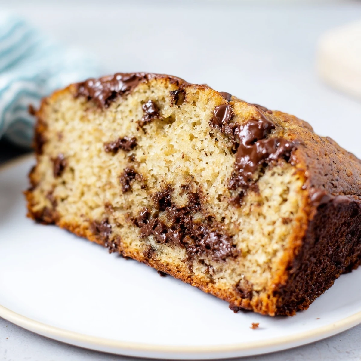 Golden-brown loaf of chocolate chip banana bread, ready to slice for a delicious treat.
