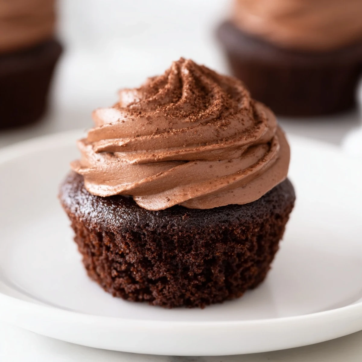Fluffy chocolate cupcakes topped with swirls of homemade chocolate frosting, ready to eat.