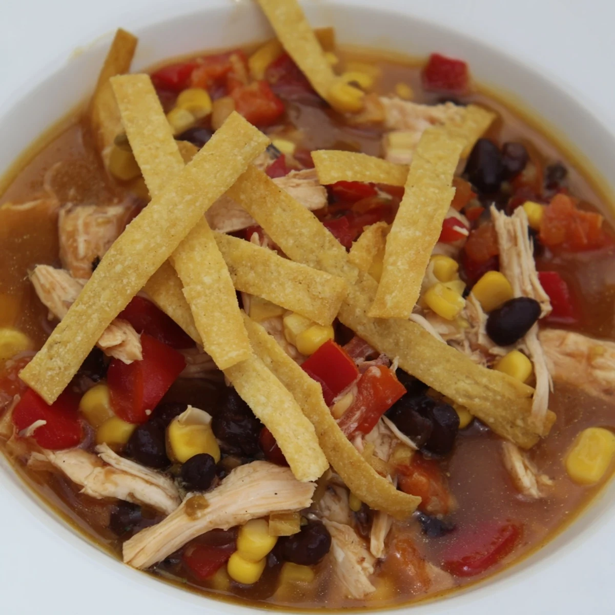 Steaming bowl of Spicy Chicken Tortilla Soup with colorful toppings and crispy tortilla strips.