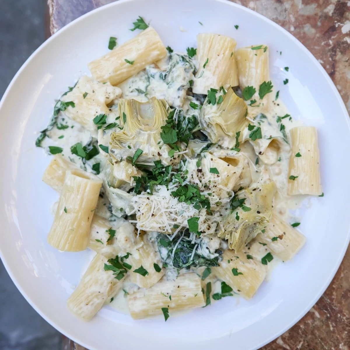 Creamy Spinach and Artichoke Pasta: hearty Italian-American pasta dish with creamy, cheesy sauce, garnished with parsley.