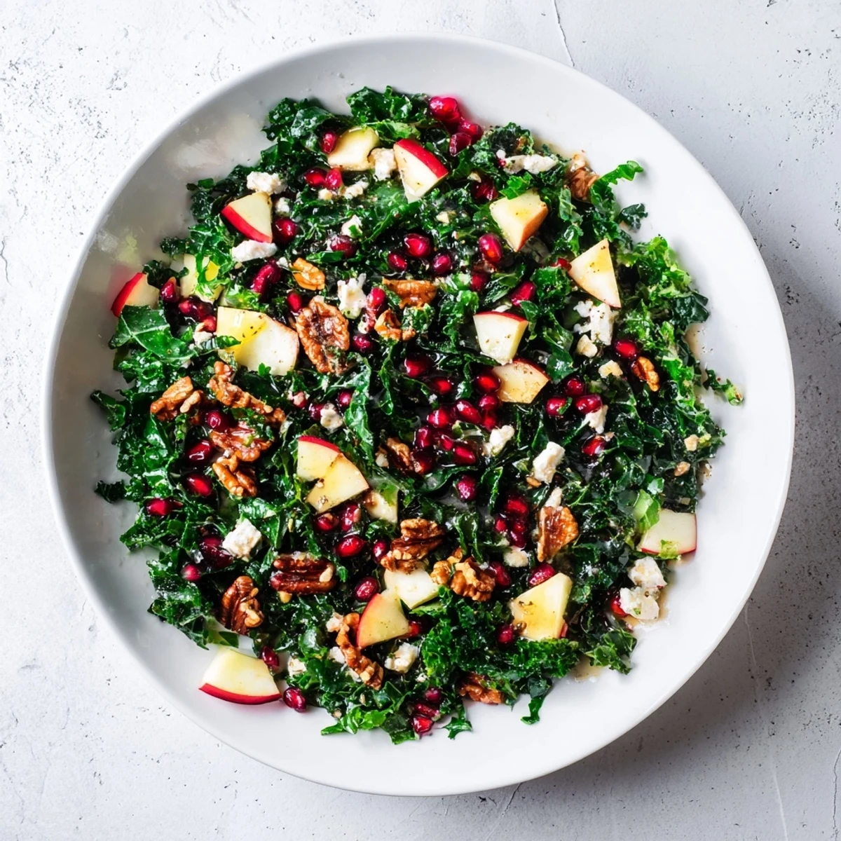 Winter kale salad with pomegranate, a festive mix of greens, pomegranate jewels, and toasted nuts.
