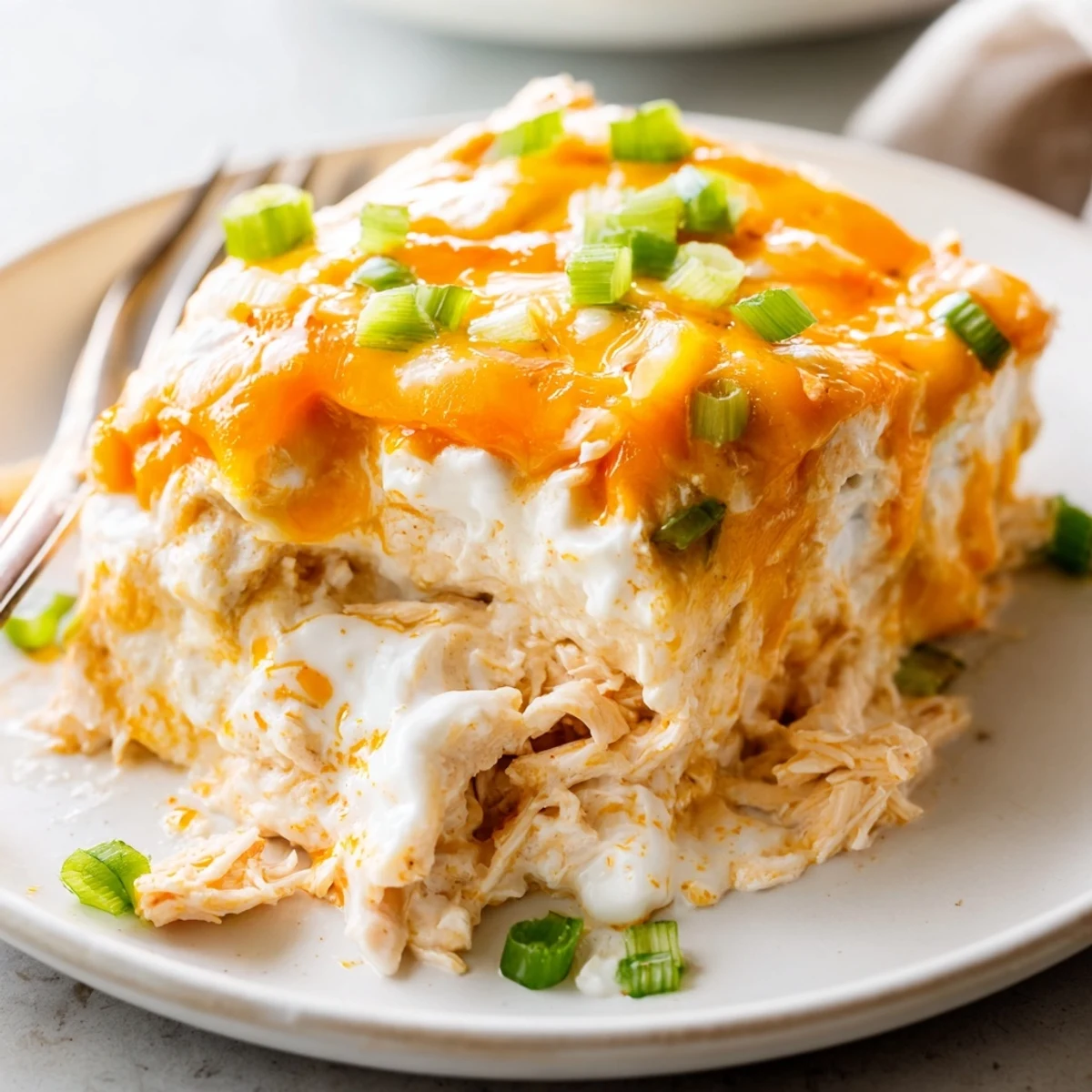 A close-up of creamy Spicy Buffalo Chicken Dip, loaded with shredded chicken and golden, melted cheese.