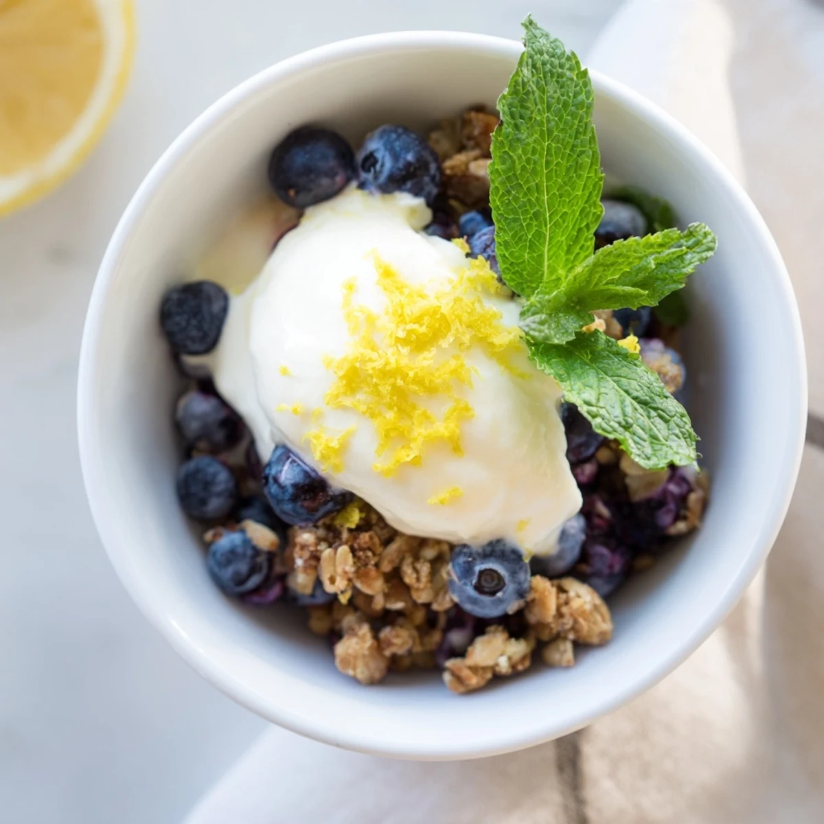 Creamy lemon yogurt and fresh blueberries layered with crunchy granola in a glass.