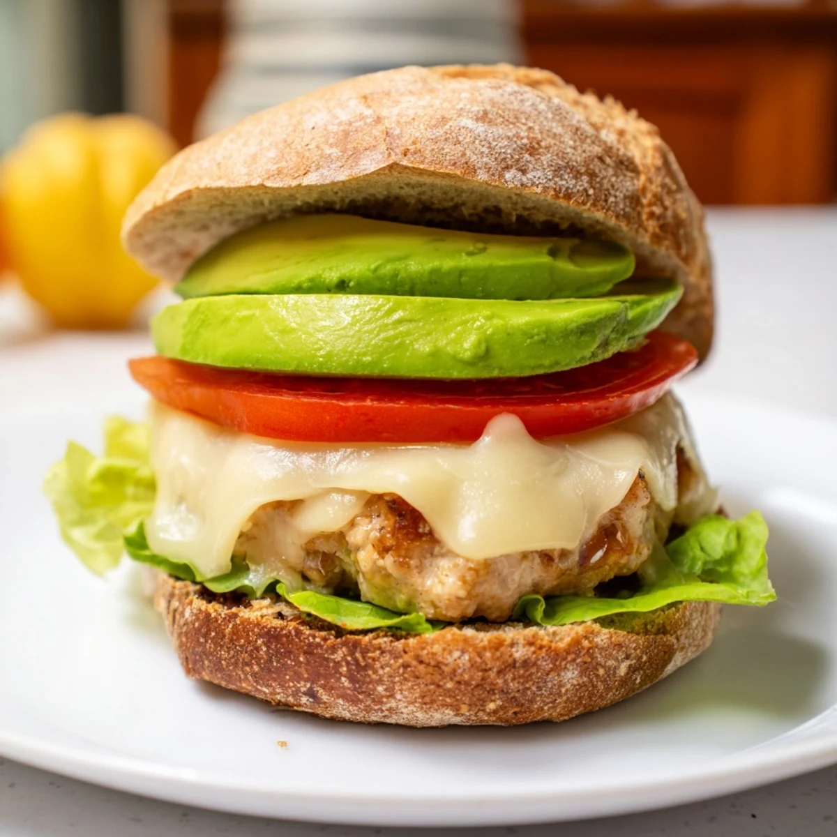 Healthy turkey burger topped with Swiss cheese and avocado, served on a toasted whole wheat bun with fresh lettuce, tomato, and red onion, perfect for a quick dinner.