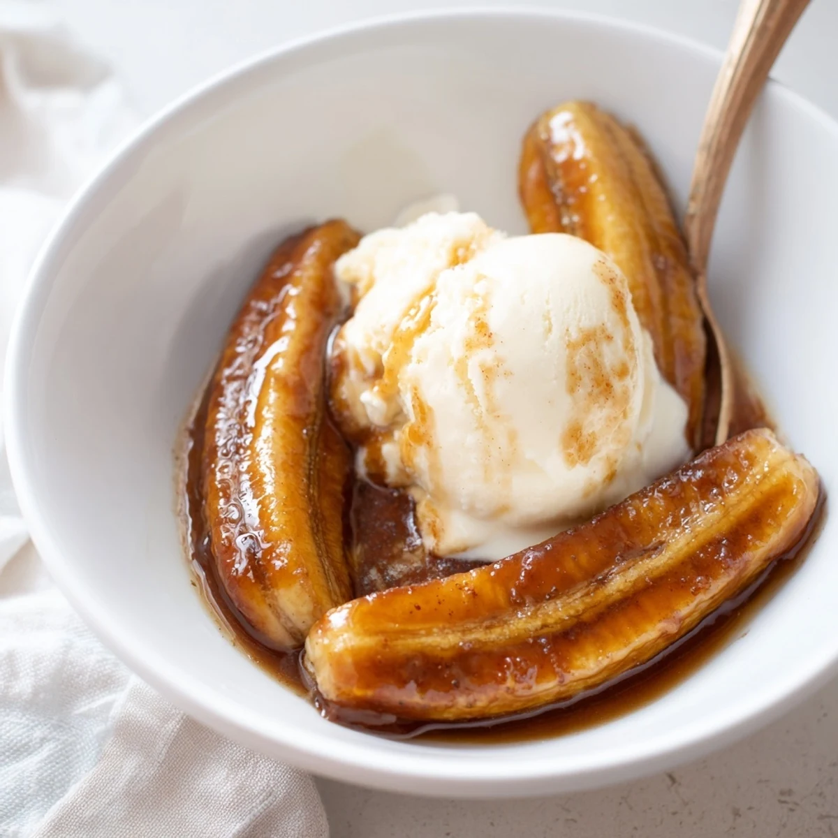 Golden brown sugar sauce bubbles around tender bananas in a skillet, the heart of this alcohol-free Classic Bananas Foster served with vanilla ice cream.