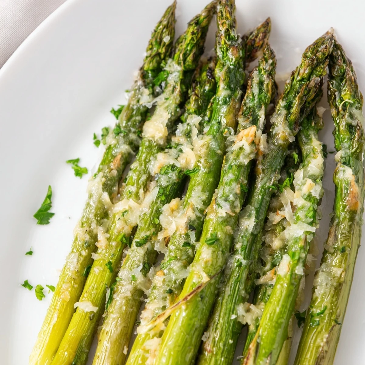 A close-up of golden Garlic Parmesan Roasted Asparagus Spears on a rustic platter, garnished with fresh parsley and shaved Parmesan.