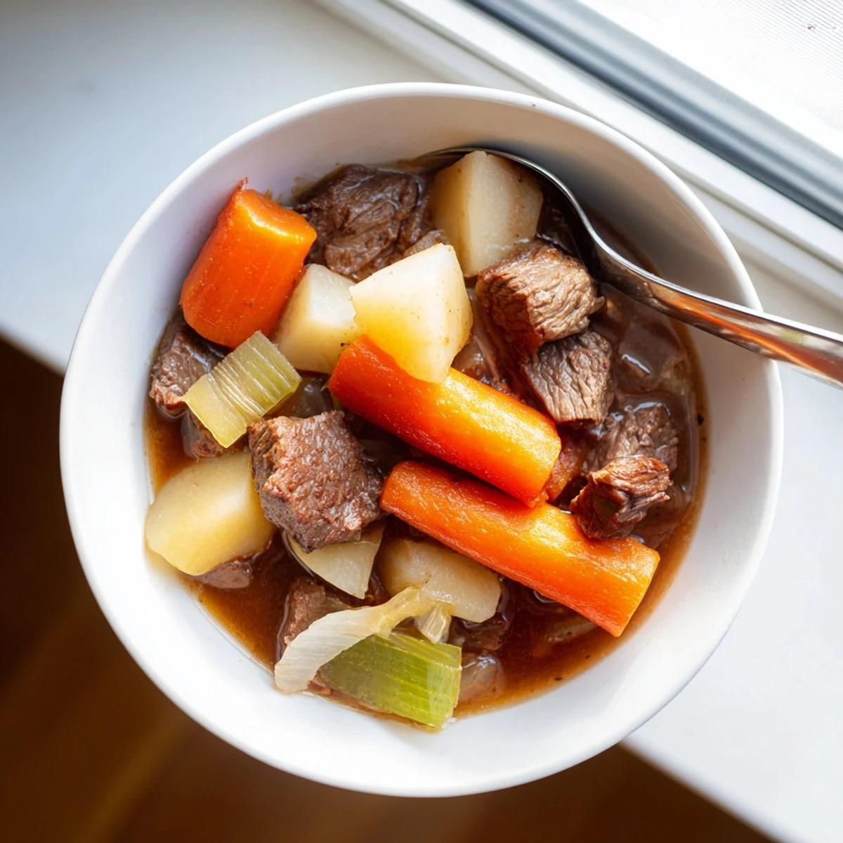 A close-up of slow cooker beef stew with root vegetables, featuring tender beef chunks, carrots, parsnips, and potatoes simmered in rich, dark broth.