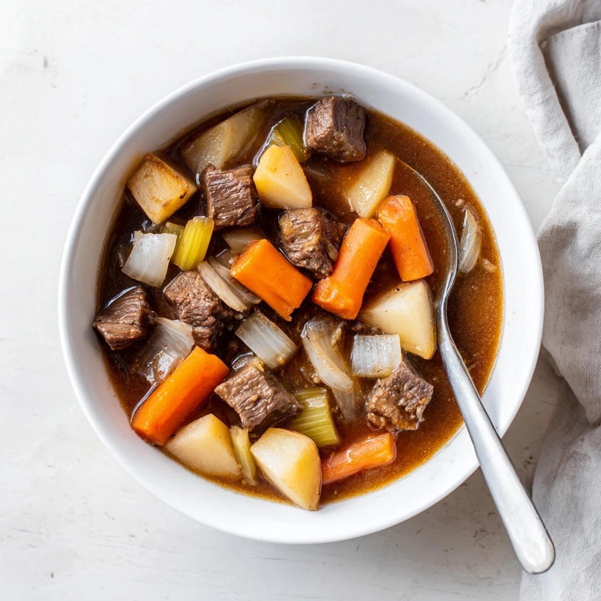 Thick, savory slow cooker beef stew with root vegetables, showcasing tender beef, colorful carrots, and potatoes in a glossy, flavorful gravy.