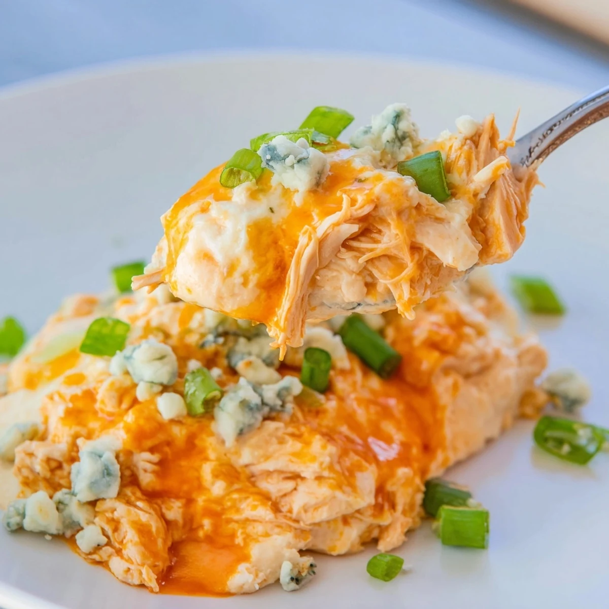 Bubbling Spicy Buffalo Chicken Dip fresh from the oven, topped with scallions and served for game day snacking.