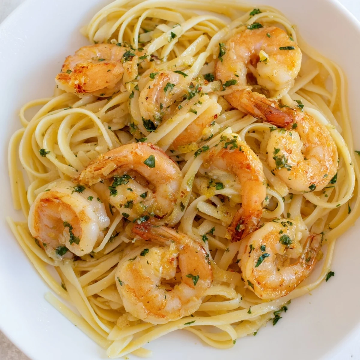 Fork-tender Date Night Shrimp Scampi glistens with garlicky wine butter sauce over al dente linguine, garnished with fresh parsley and lemon wedges on a romantic table setting.