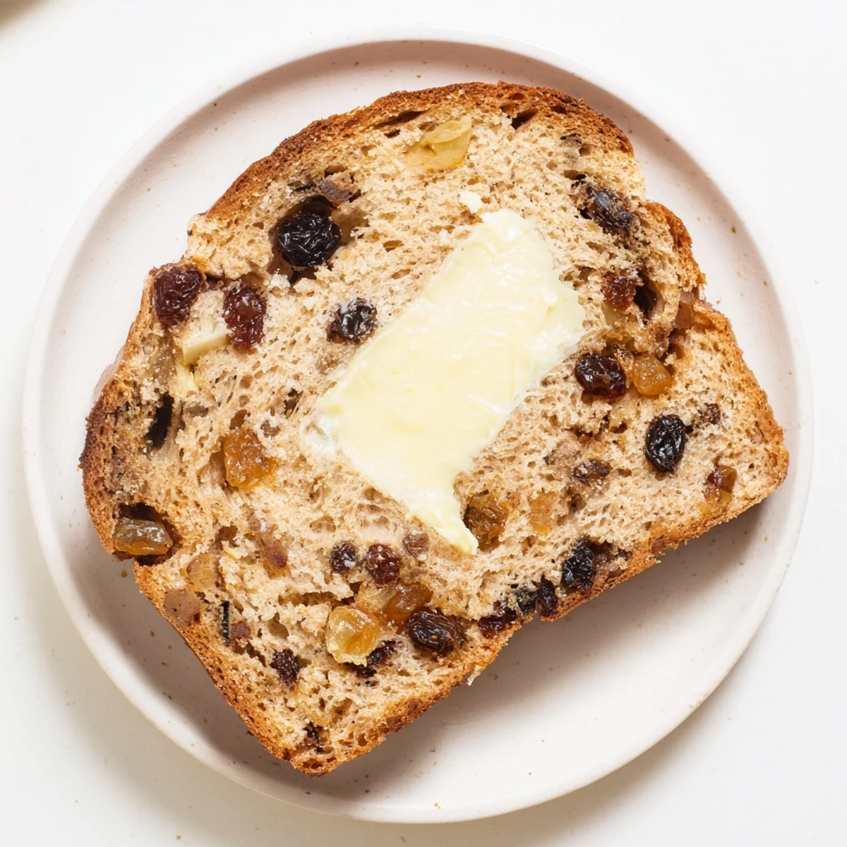 The baked Irish Barmbrack fruit bread loaf rests on a wooden cooling rack, showcasing its golden-brown crust and abundant plump, tea-soaked raisins.