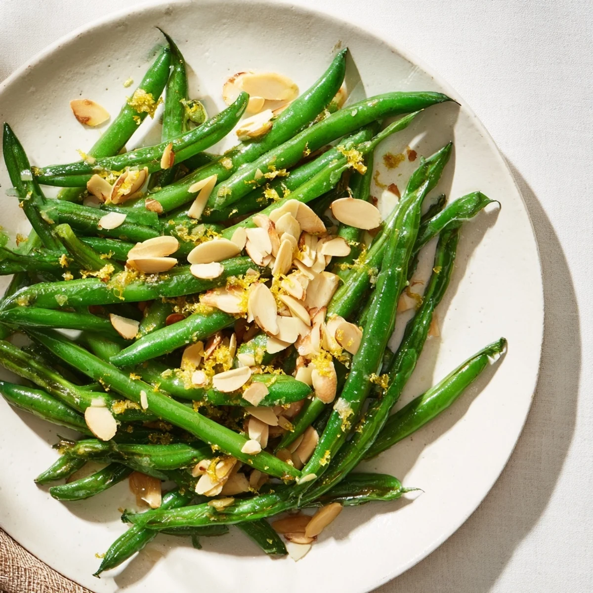Bright green beans tossed with lemon and crunchy toasted almonds are served warm alongside grilled chicken for dinner.