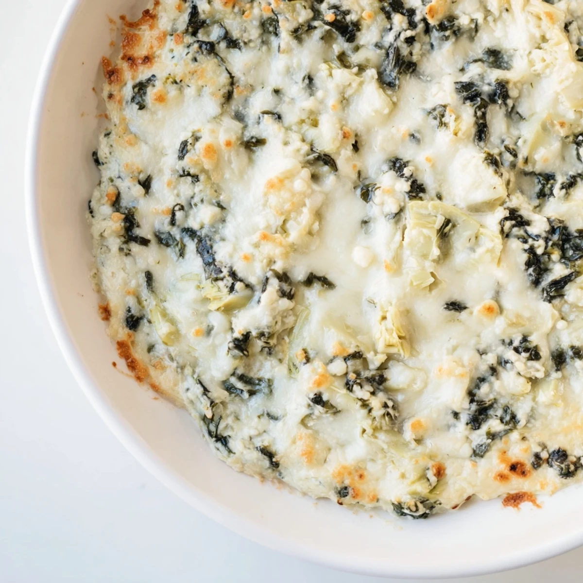A warm, golden-baked Creamy Spinach and Artichoke Dip emerges from the oven, bubbling in a ceramic dish.  