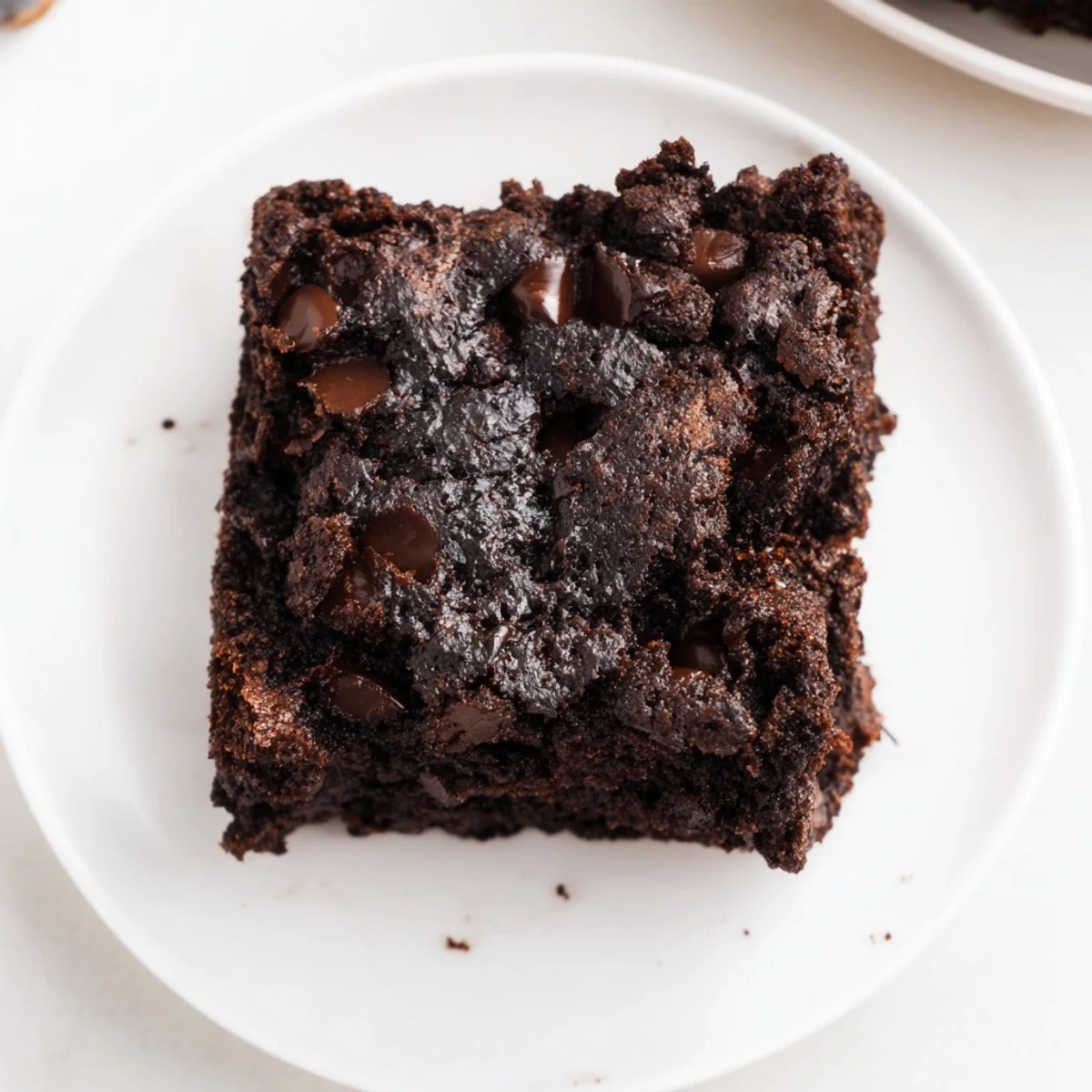 A close-up of gluten-free almond flour brownies cut into squares, showing a moist, rich crumb and a dusting of powdered sugar.