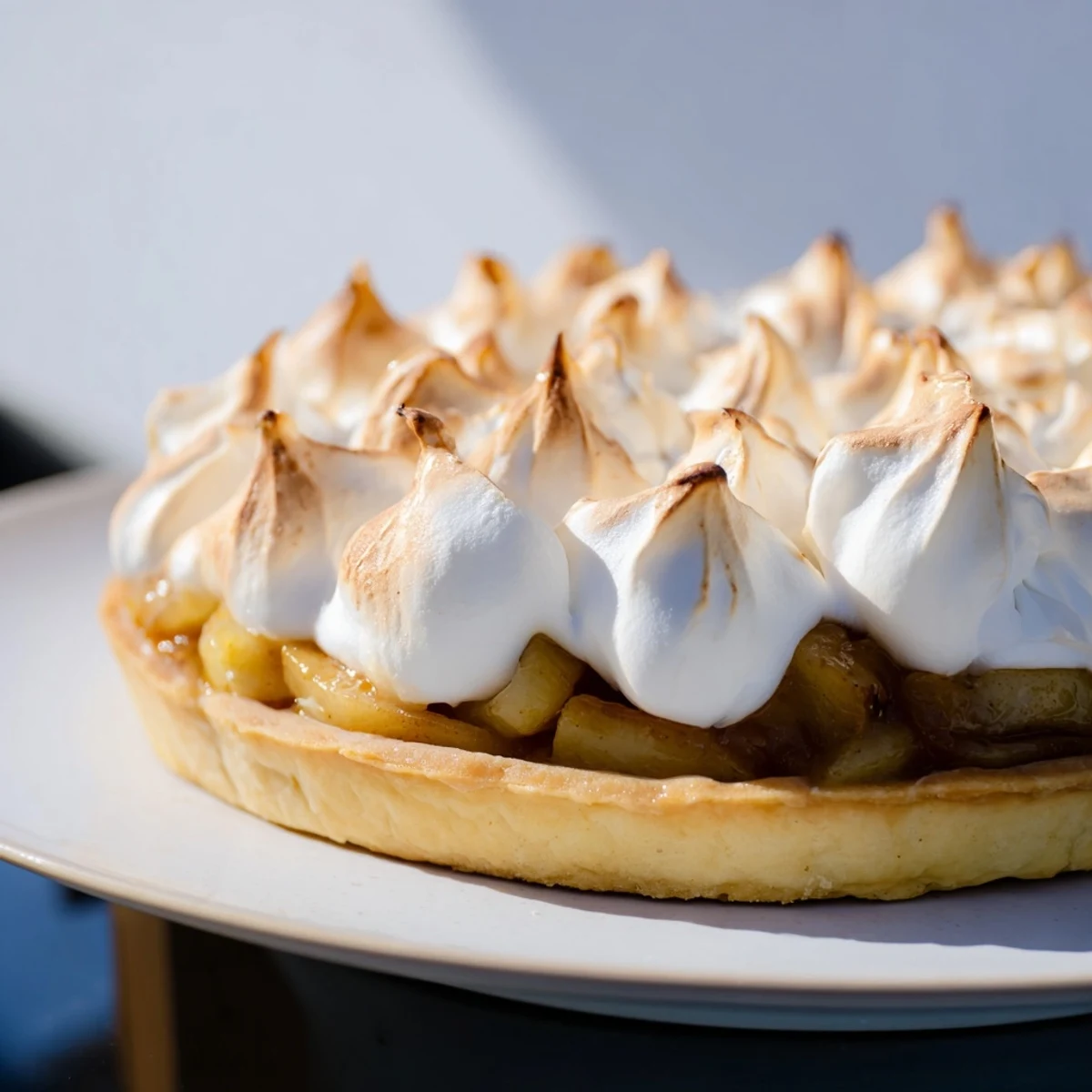 A slice of Irish Apple Amber Tart with Meringue Top reveals golden baked peaks over spiced apple compote in a buttery crust.