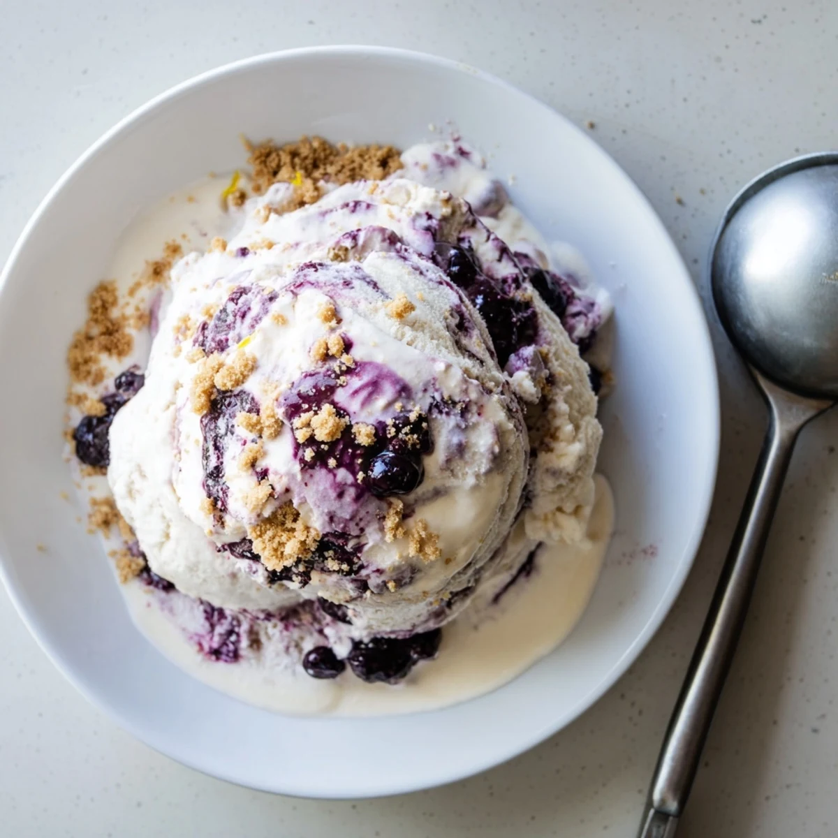 Swirled Lemon Blueberry Cheesecake Ice Cream in a freezer container ready to serve.