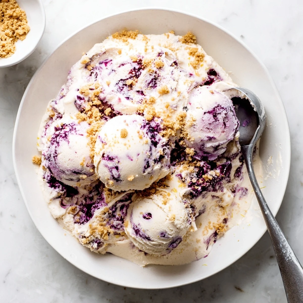 Scoops of homemade Lemon Blueberry Cheesecake Ice Cream served with fresh blueberries.