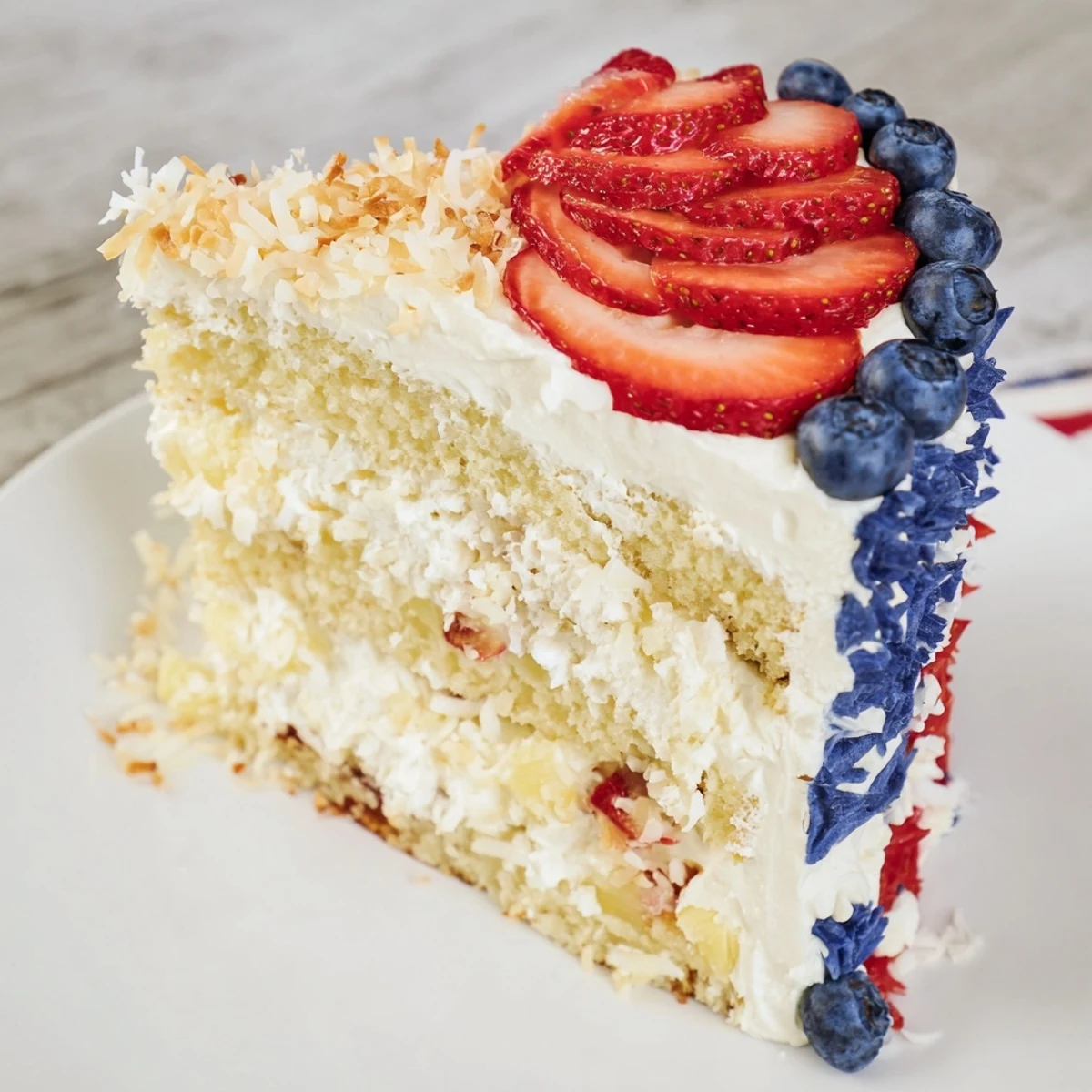 Golden layer cake Pineapple Coconut God Bless America Cake drizzled with frosting and toasted coconut flakes.