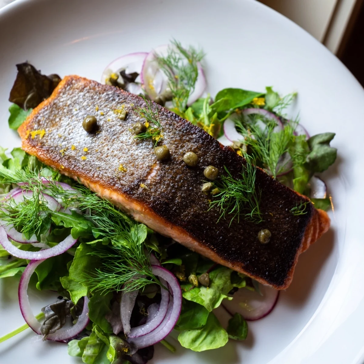 Golden-brown crispy skin Tasmanian Atlantic salmon rests atop a fresh lemony herb salad with dill and parsley.