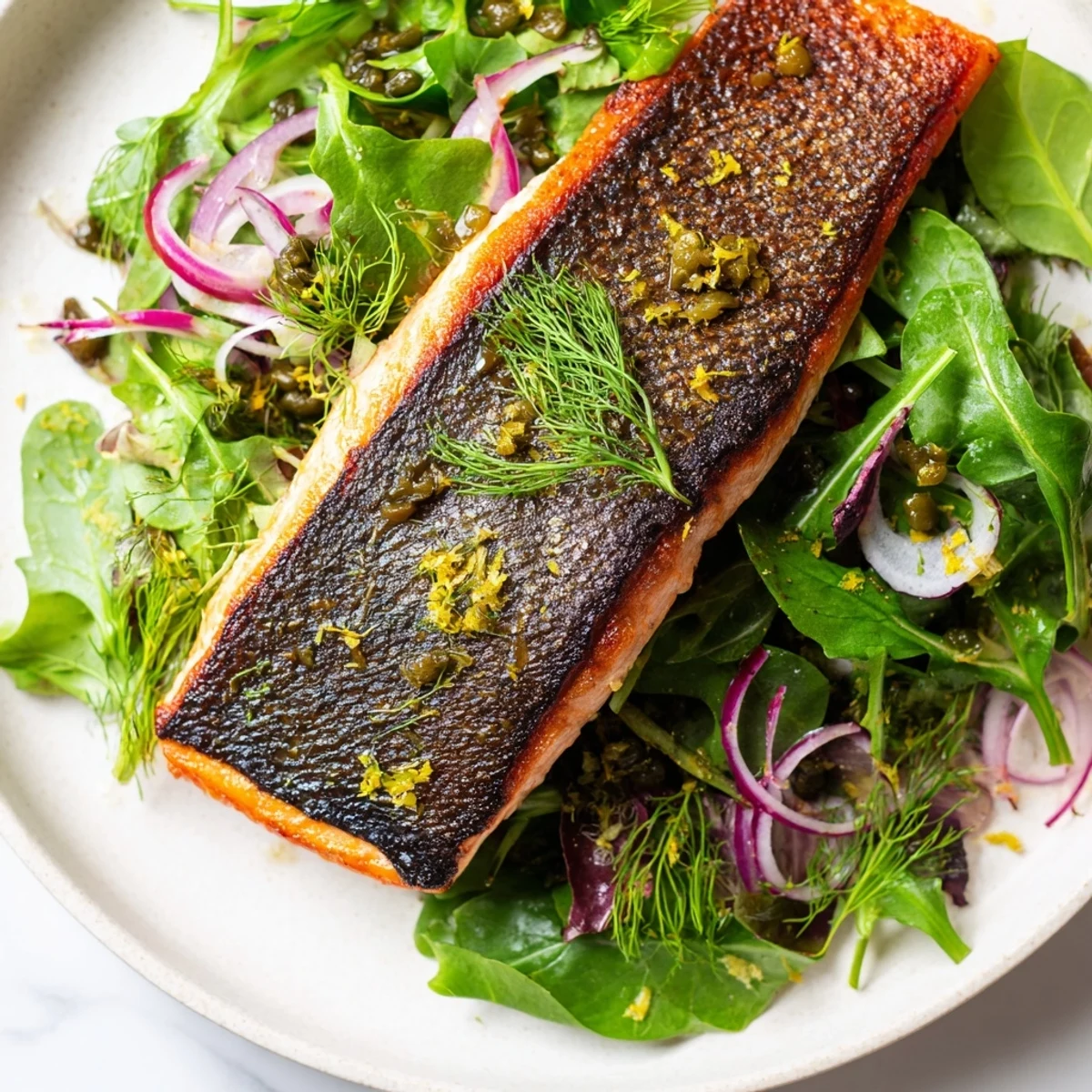 In a skillet, Tasmanian Atlantic salmon sizzles with crispy skin, paired with a vibrant arugula and red onion salad.