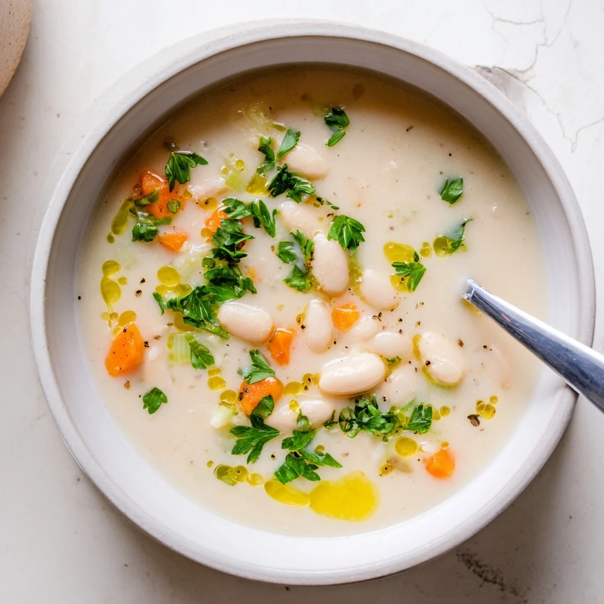 Creamy Cozy Rosemary Garlic White Bean Soup served in a rustic mug with olive oil drizzle