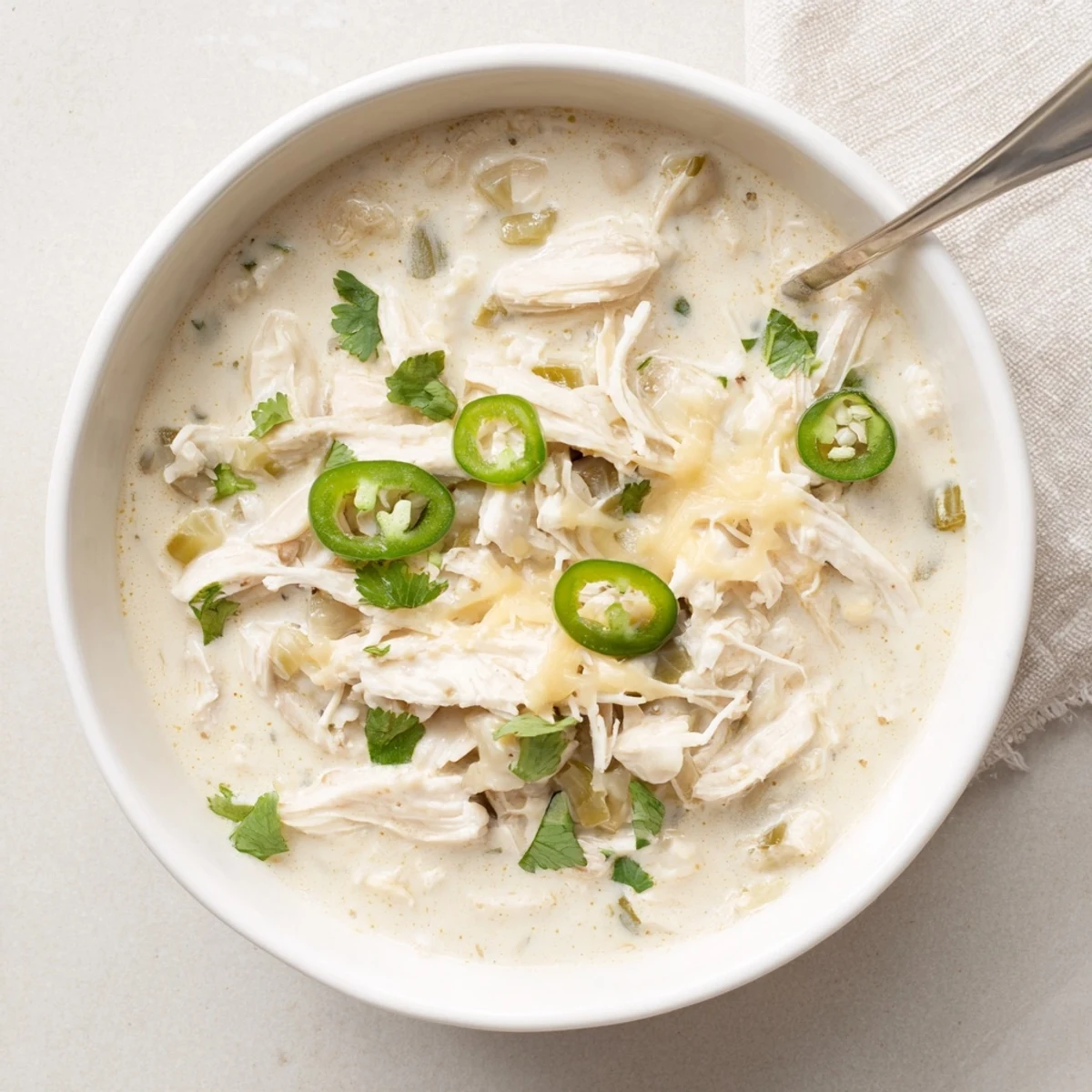 Creamy white chicken chili simmering in a pot with tender shredded chicken and green chiles