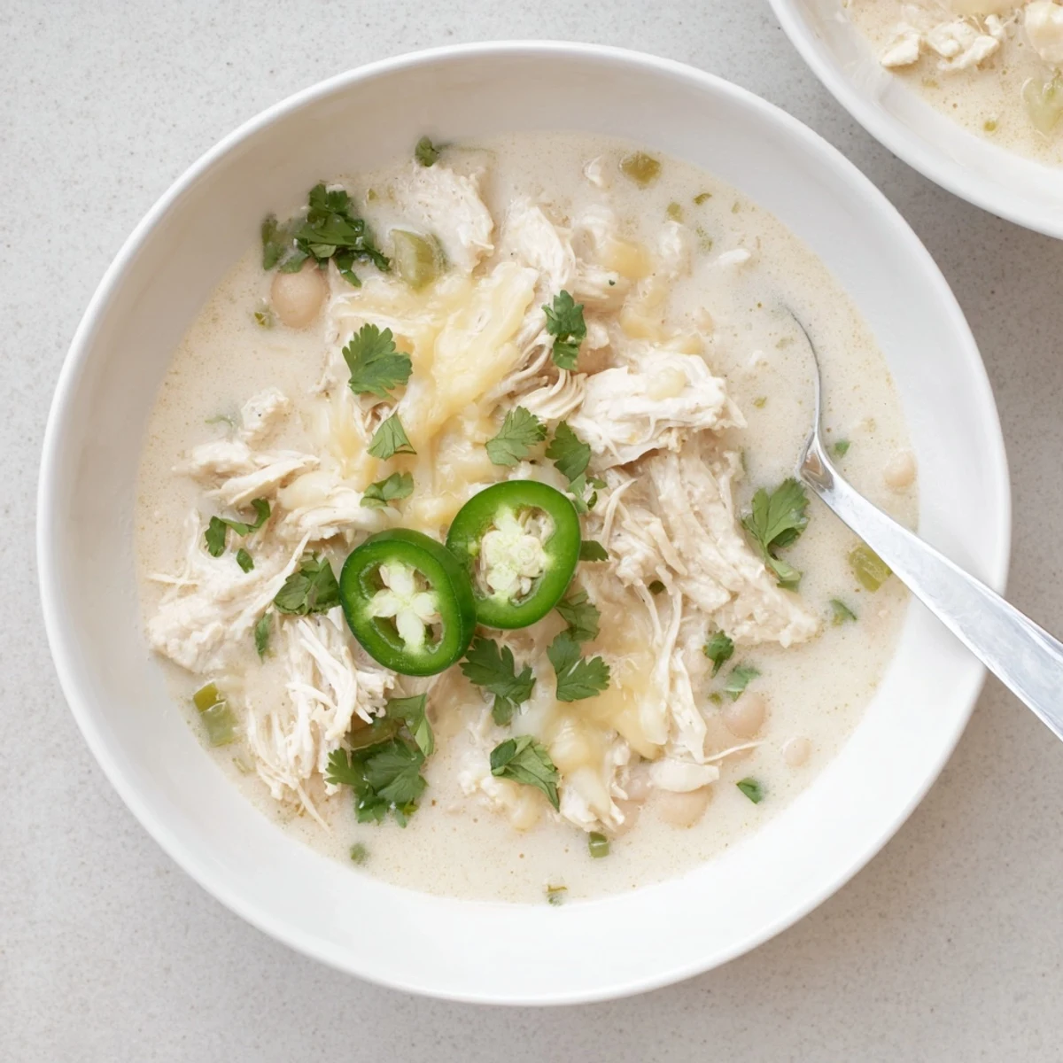 Steaming bowl of keto white chicken chili topped with fresh cilantro and Monterey Jack cheese
