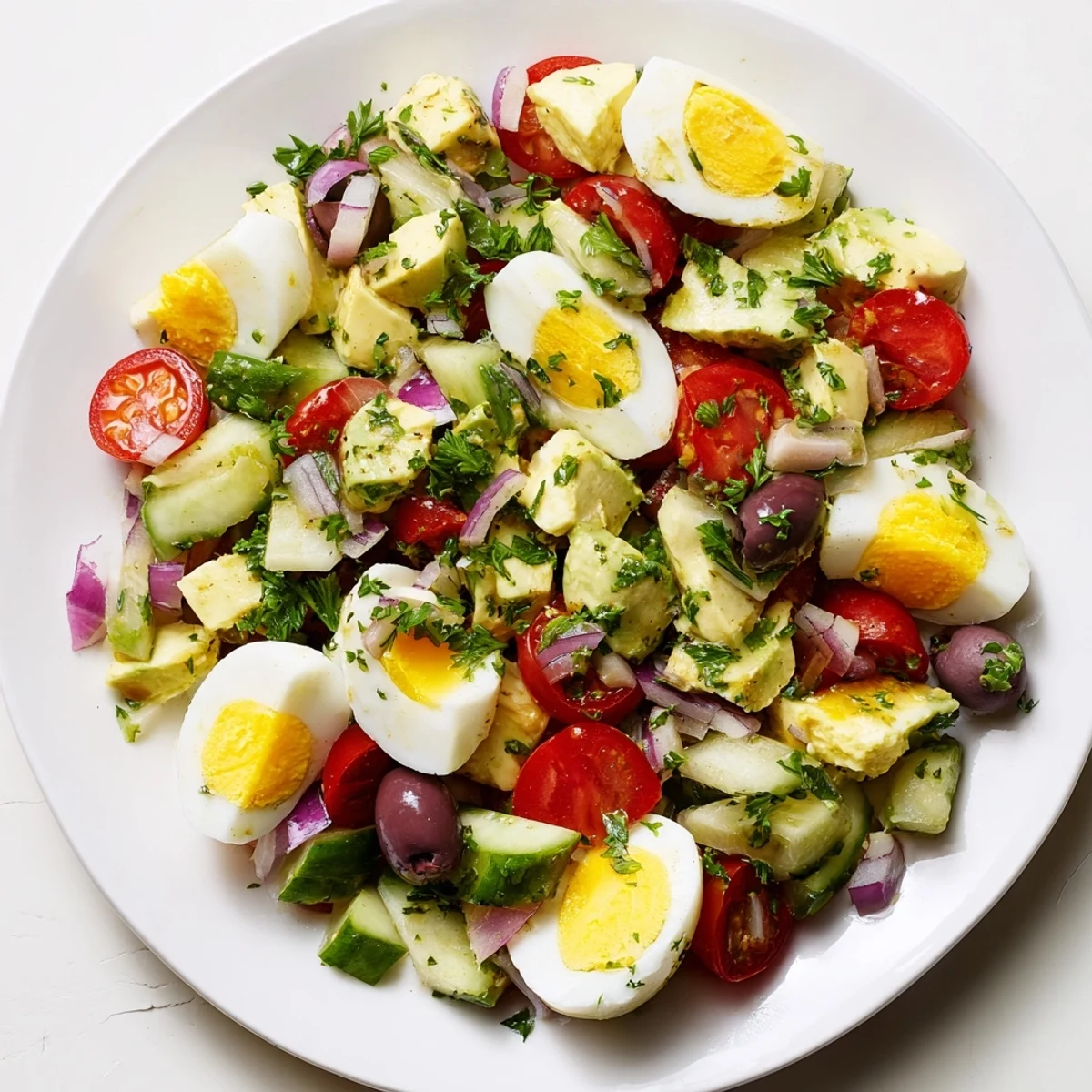 Vibrant bowl of zesty Mediterranean avocado egg salad featuring chunky hard-boiled eggs, ripe avocado, cherry tomatoes, and Kalamata olives