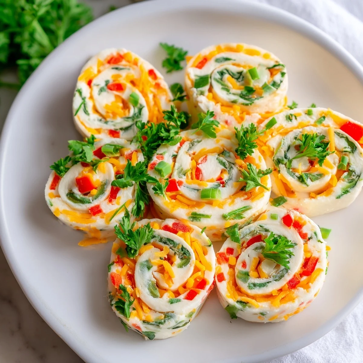 Close-up view of spiral cream cheese pinwheels revealing colorful diced bell peppers and green onions