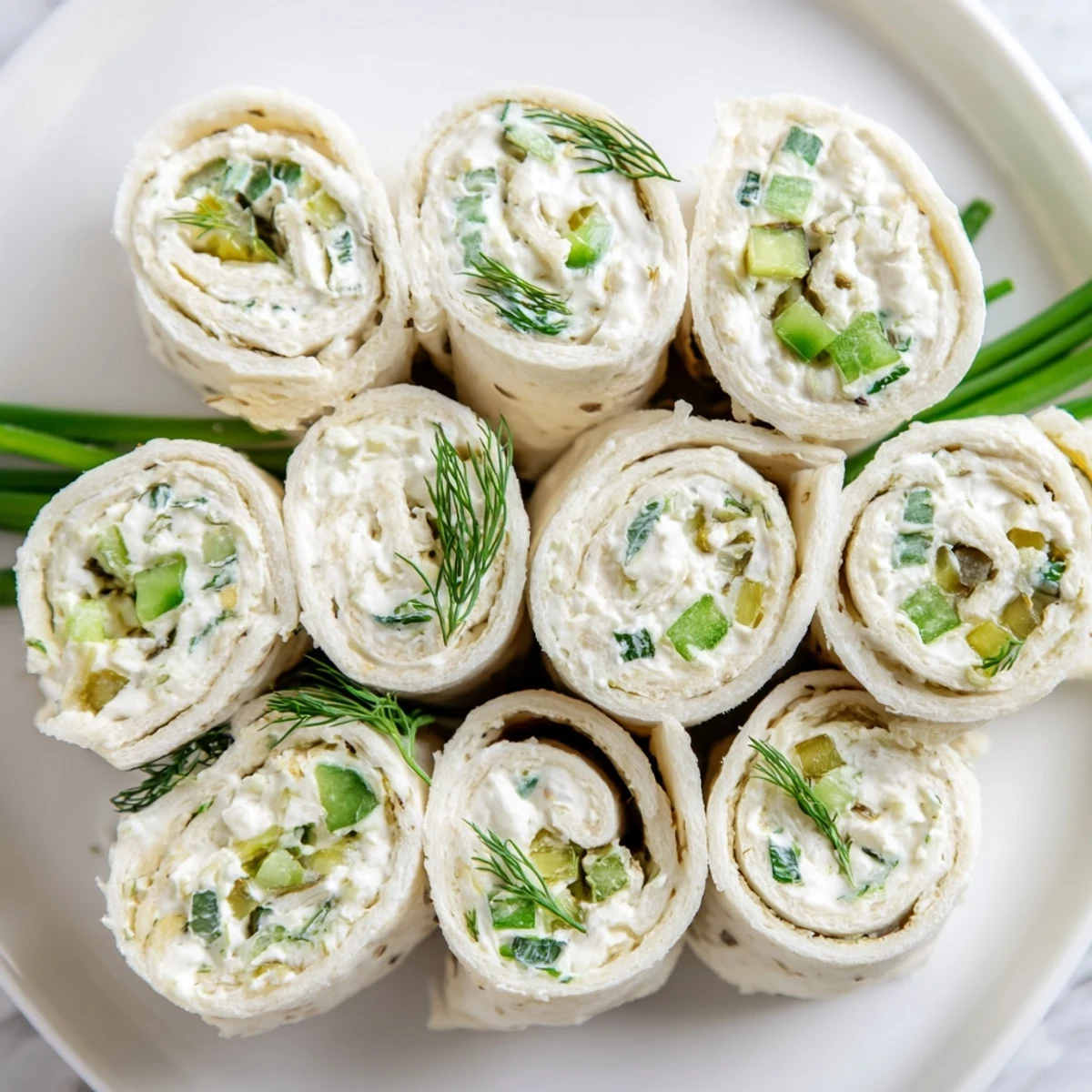 Tight spiral tortilla rolls filled with tangy dill pickle cream cheese mixture