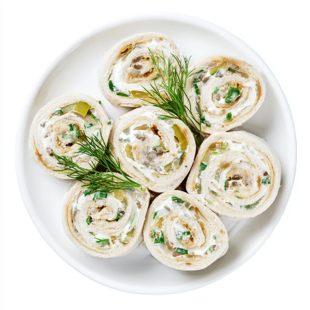 Fresh pickle dip pinwheels sliced on white platter with green flecks visible
