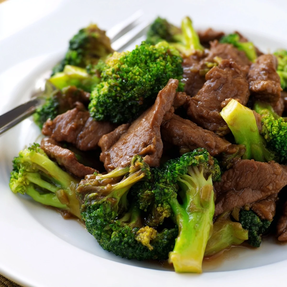 Rich glossy beef and broccoli stir fry sauce coats tender beef strips and fresh green broccoli florets in a dark savory glaze