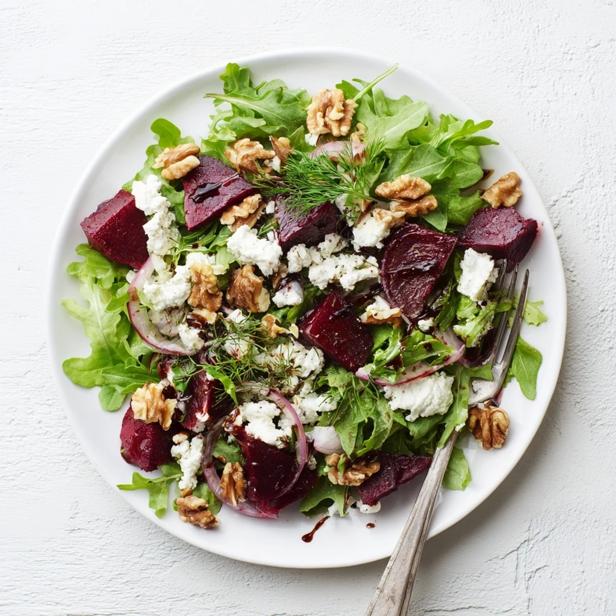 Colorful ultimate beet salad featuring roasted red beets, creamy goat cheese, toasted walnuts, and fresh mixed greens drizzled with balsamic vinaigrette