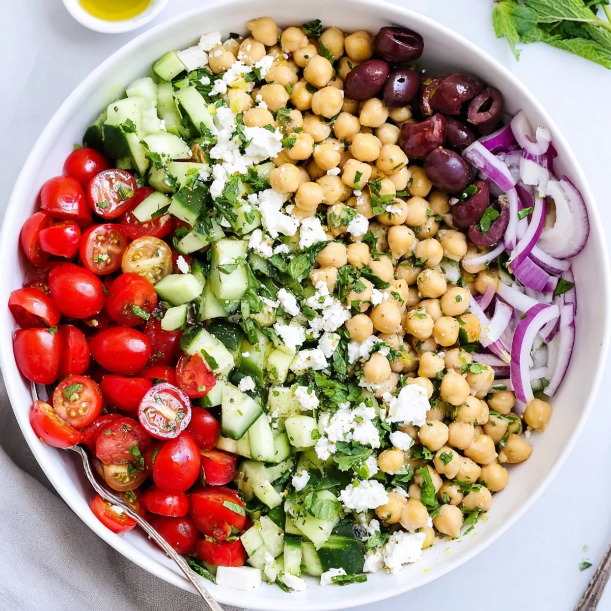 Colorful Mediterranean chickpea salad bowl featuring fresh vegetables, olives, and herbs in lemon dressing