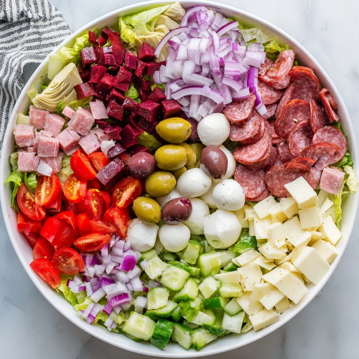 Hearty antipasti chopped salad featuring cured meats, roasted peppers, and tangy pepperoncini