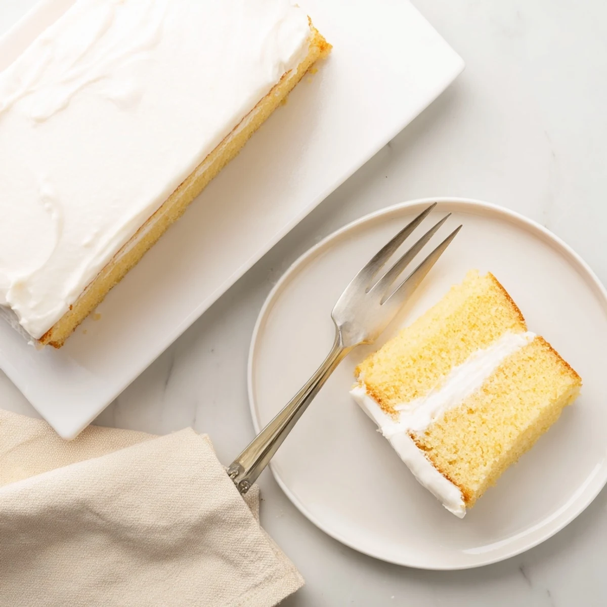 Light and airy homemade Church Cake slice topped with creamy buttercream frosting on a white plate