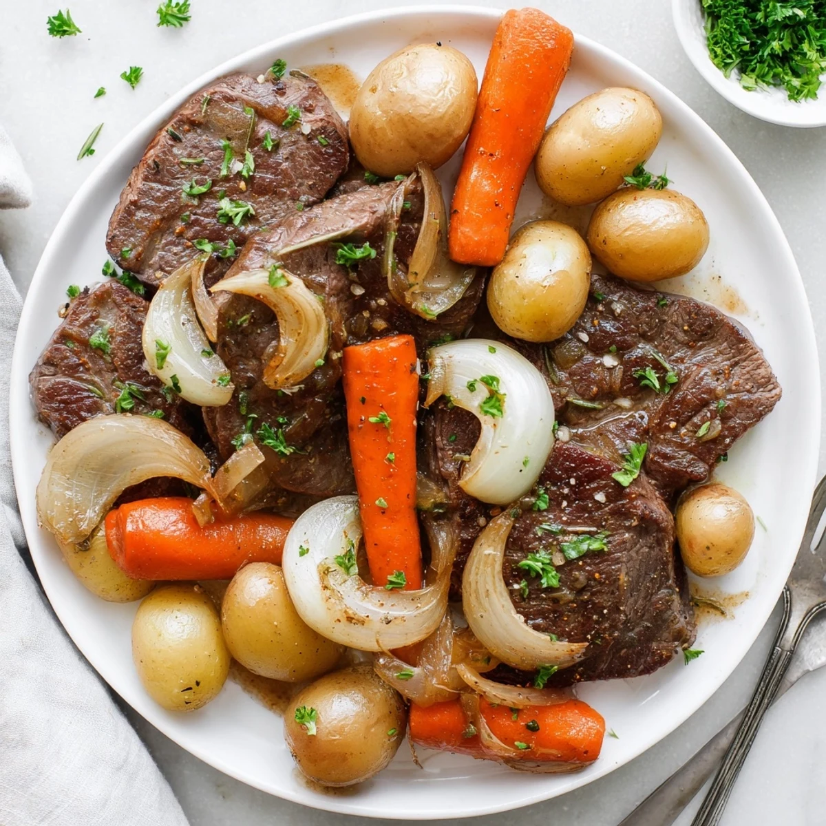 Comforting slow cooker steak and potatoes garnished with fresh parsley, showcasing melt-in-your-mouth beef and golden vegetables