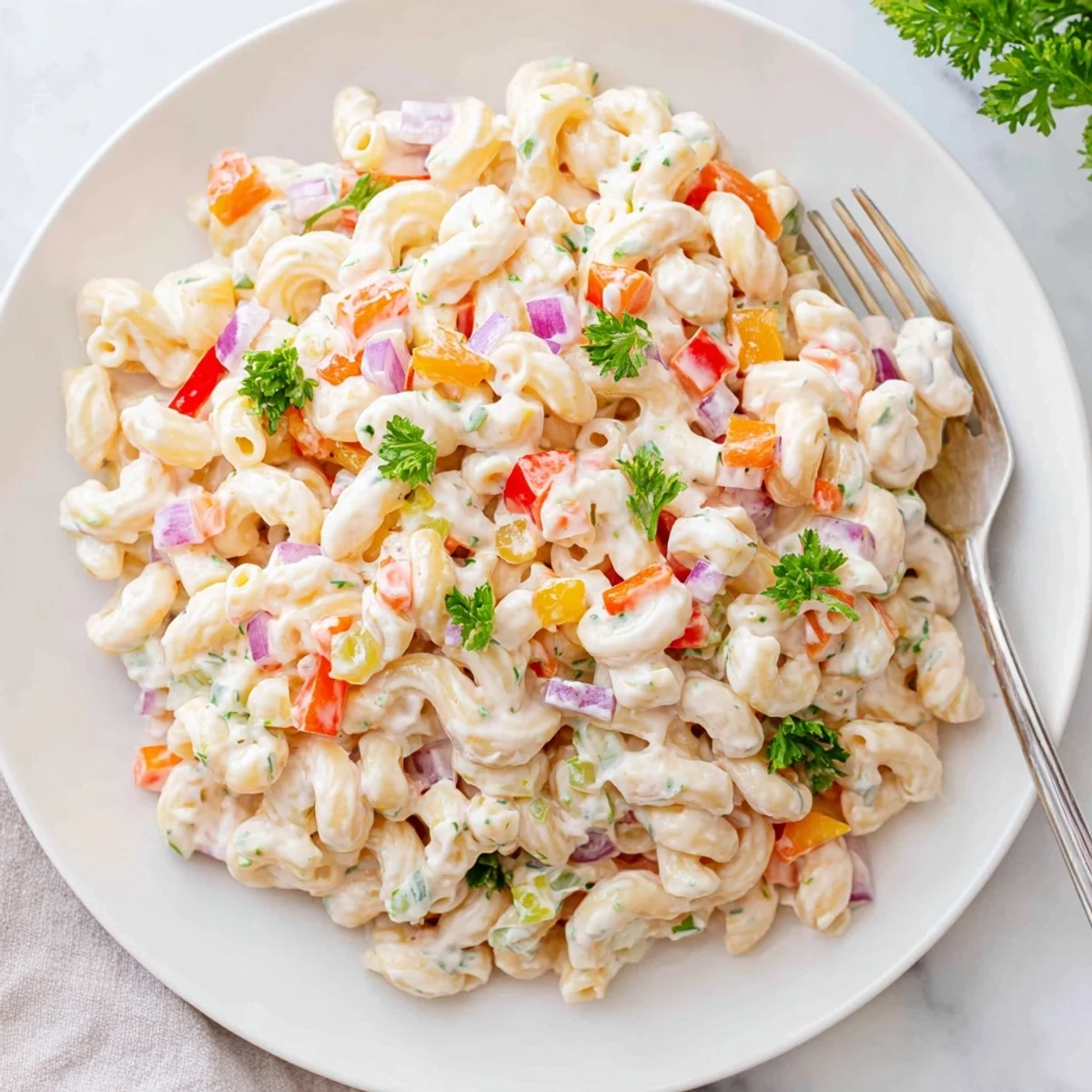 Creamy tangy macaroni salad loaded with colorful diced vegetables and fresh parsley garnish
