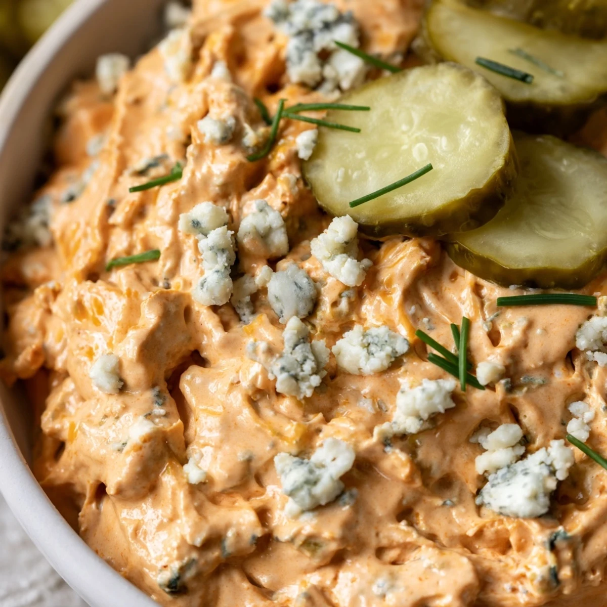 Creamy buffalo pickle dip served in a bowl with crispy chips and fresh vegetables