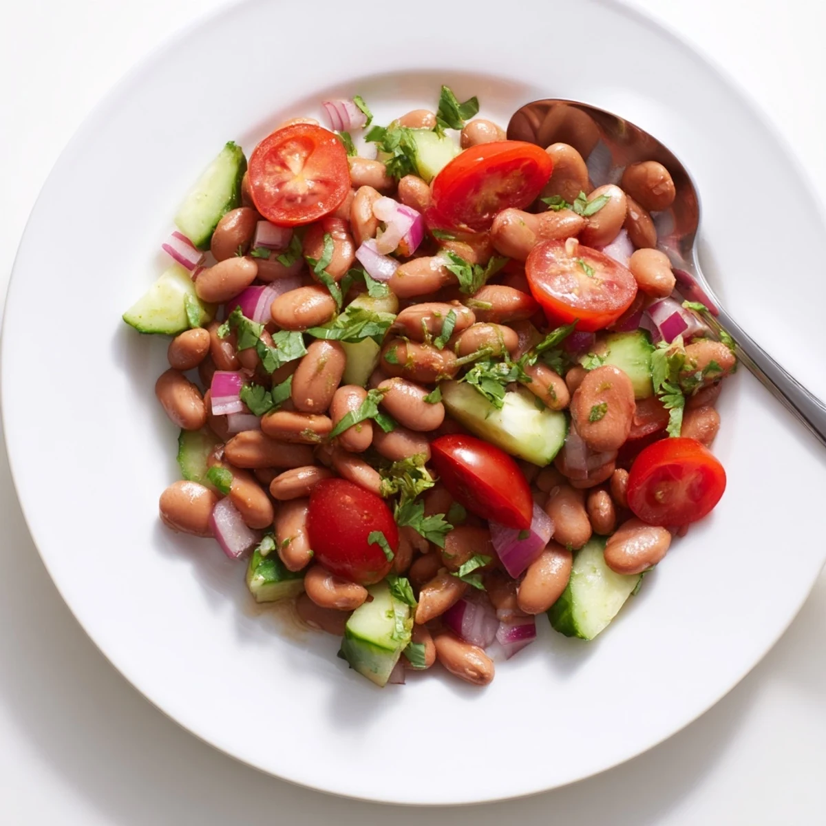Colorful pinto bean salad tossed with crisp veggies and bright lime dressing in a rustic bowl