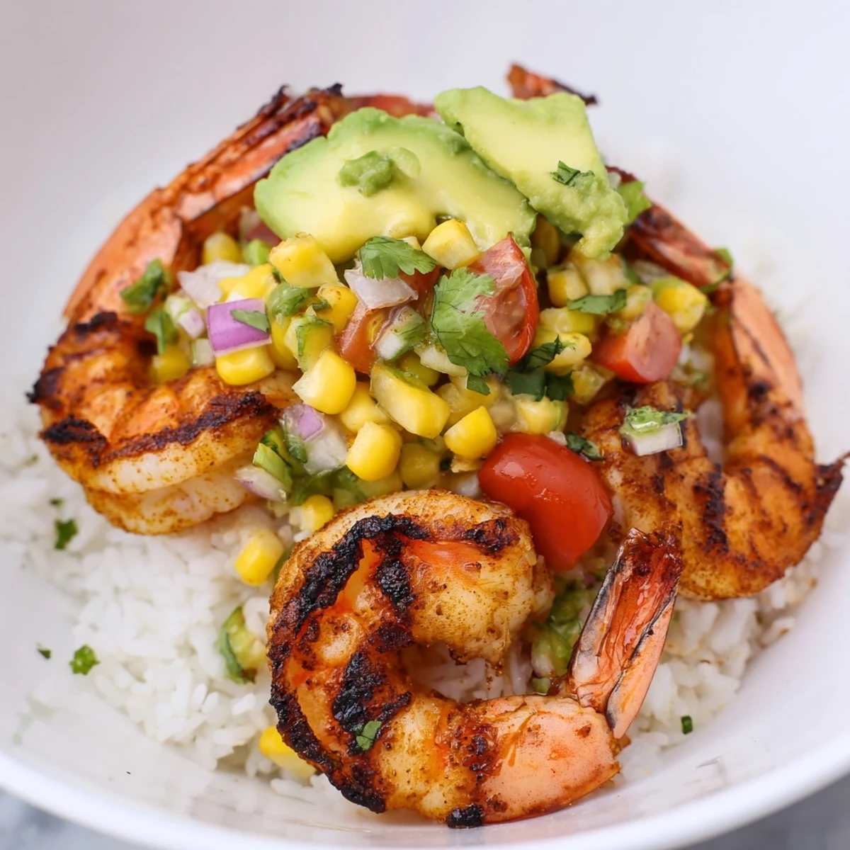Charred grilled shrimp bowl with avocado corn salsa over fluffy white rice