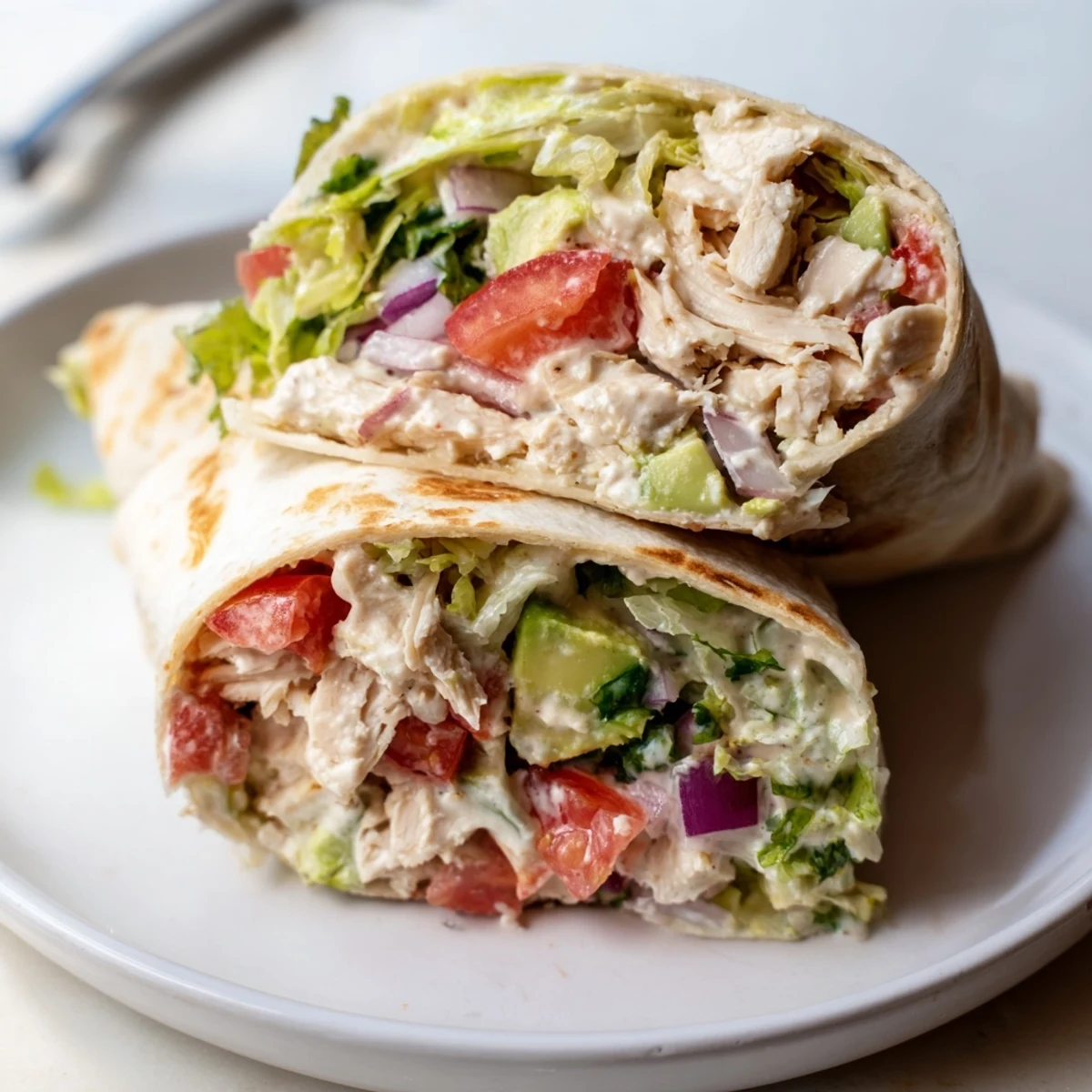 Pan-seared Chicken Avocado Ranch Burritos served halved with cilantro and lime wedges