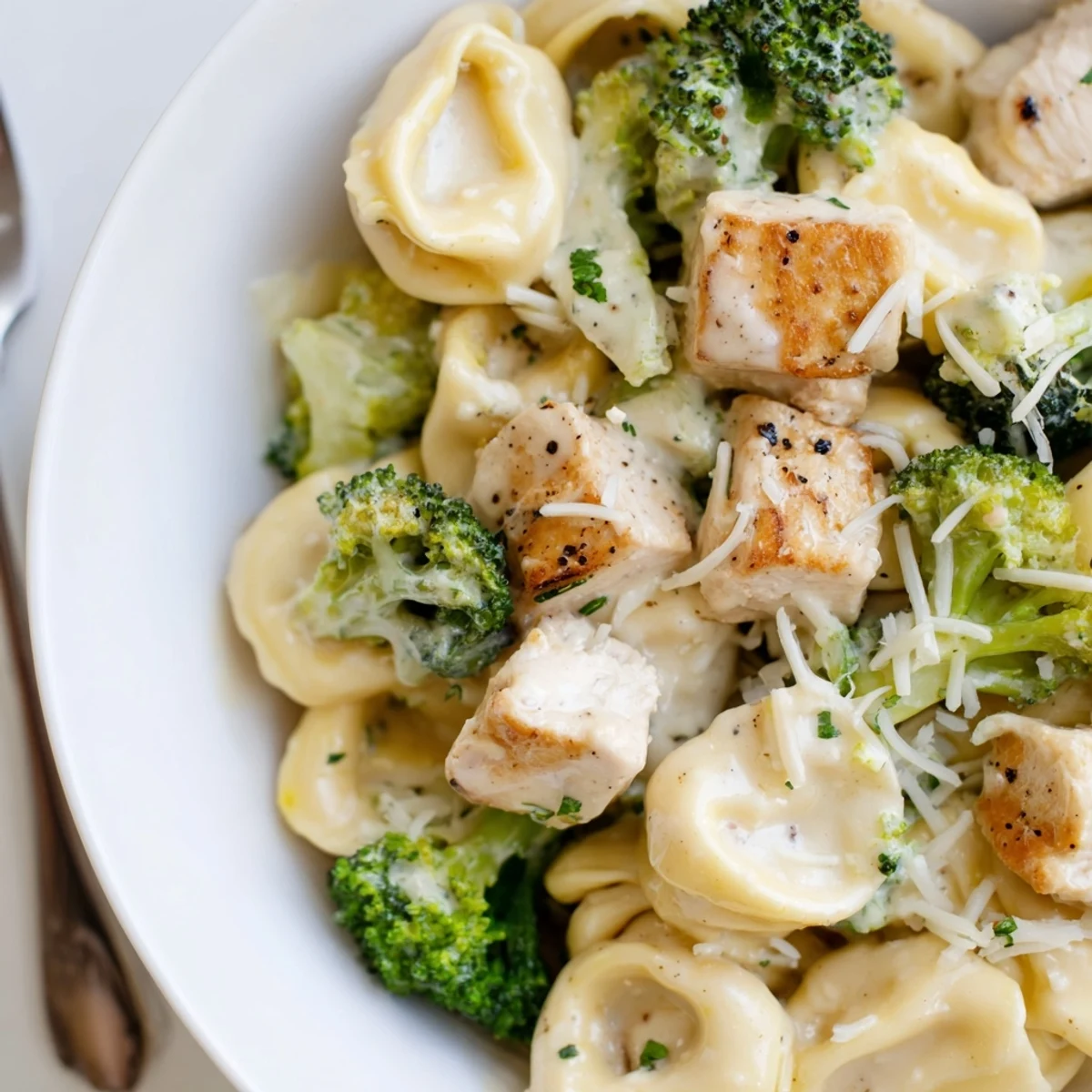 Skillet full of steaming Creamy Garlic Parmesan Tortellini Chicken Broccoli Recipe, fragrant and rich.