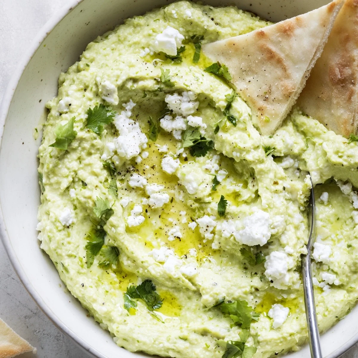Spoonful of Creamy Avocado Feta Dip on pita chip, bright lime aroma