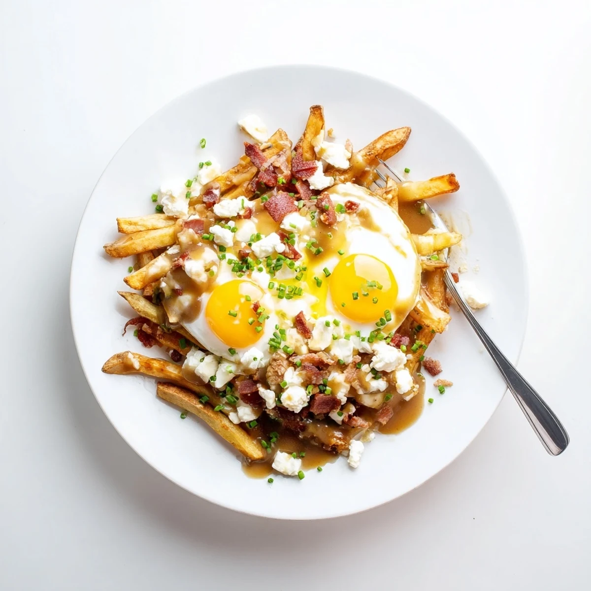 Hearty breakfast poutine with crispy potato fries, runny eggs, bacon crumbles, and warm beef gravy