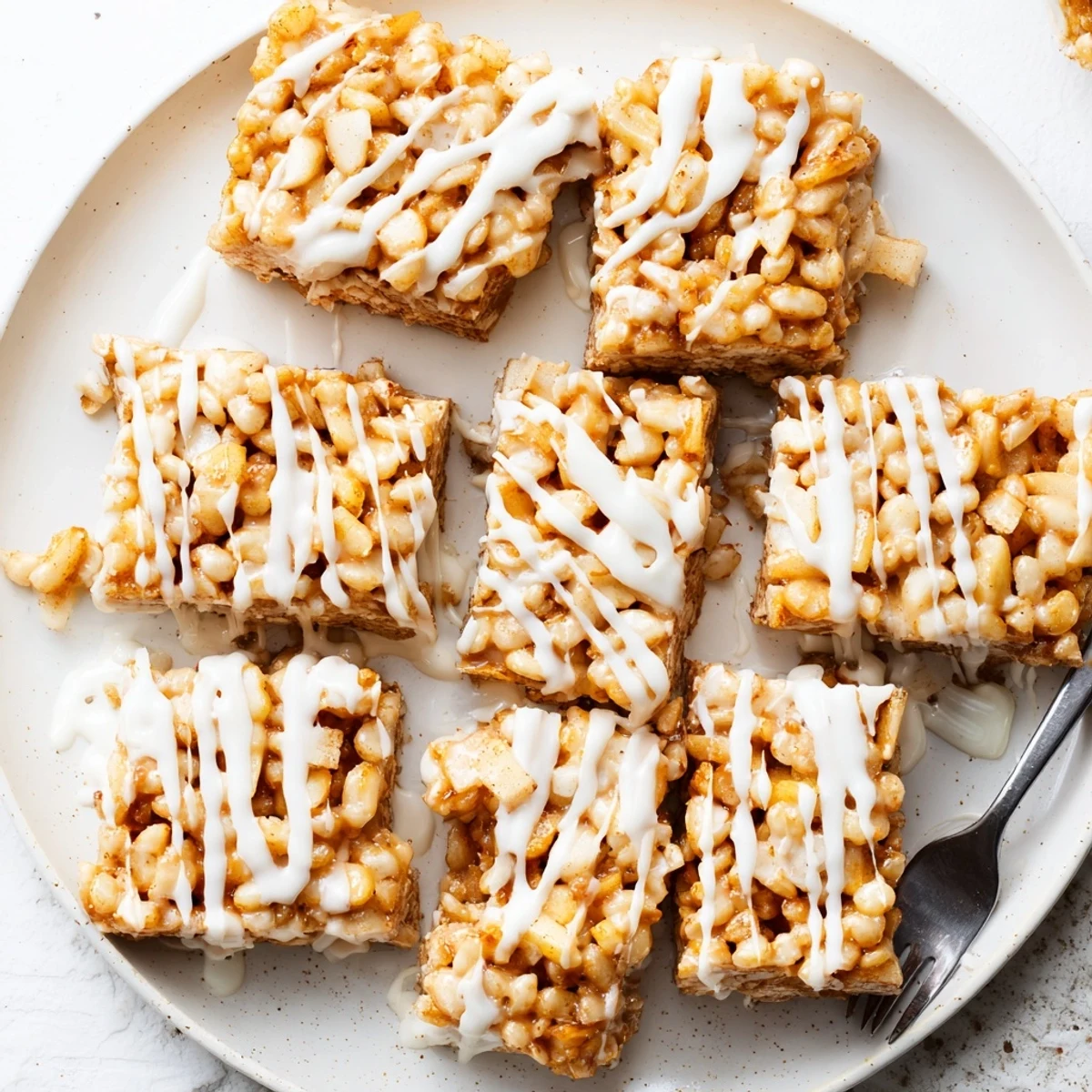 Golden apple pie Rice Krispie treats drizzled with white chocolate on a white plate