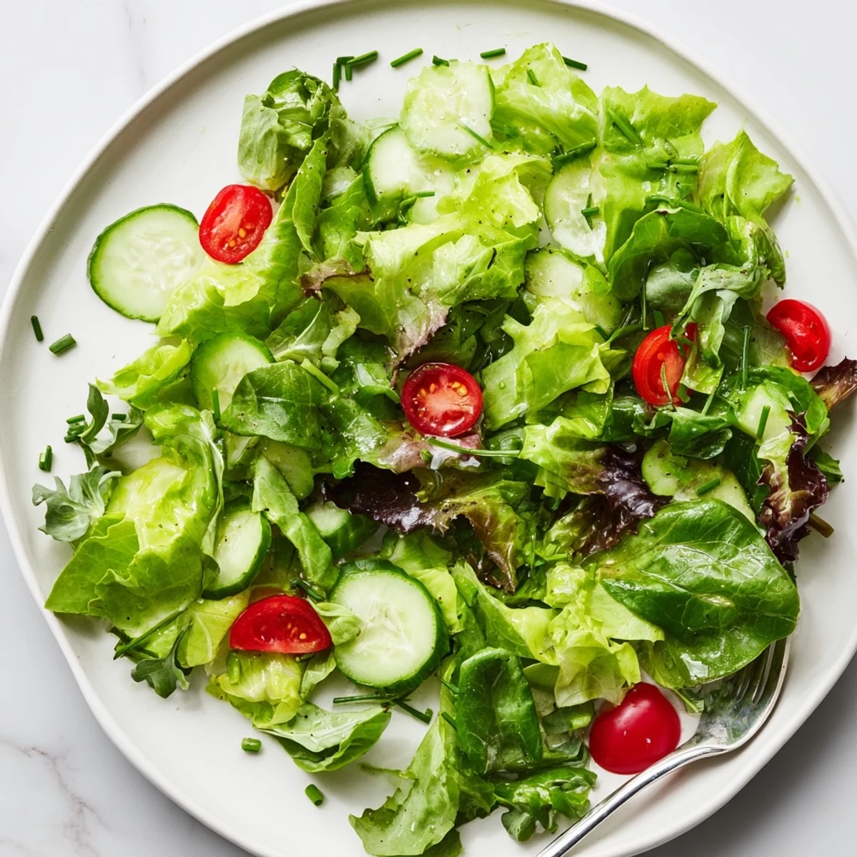 Fresh bowl showing Simple Green Salad Recipe with sliced cucumber and chives