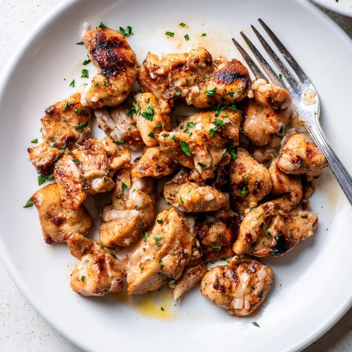 Plate of Grilled Chicken Bites With Creamy Garlic Sauce, drizzled, garnished with parsley.