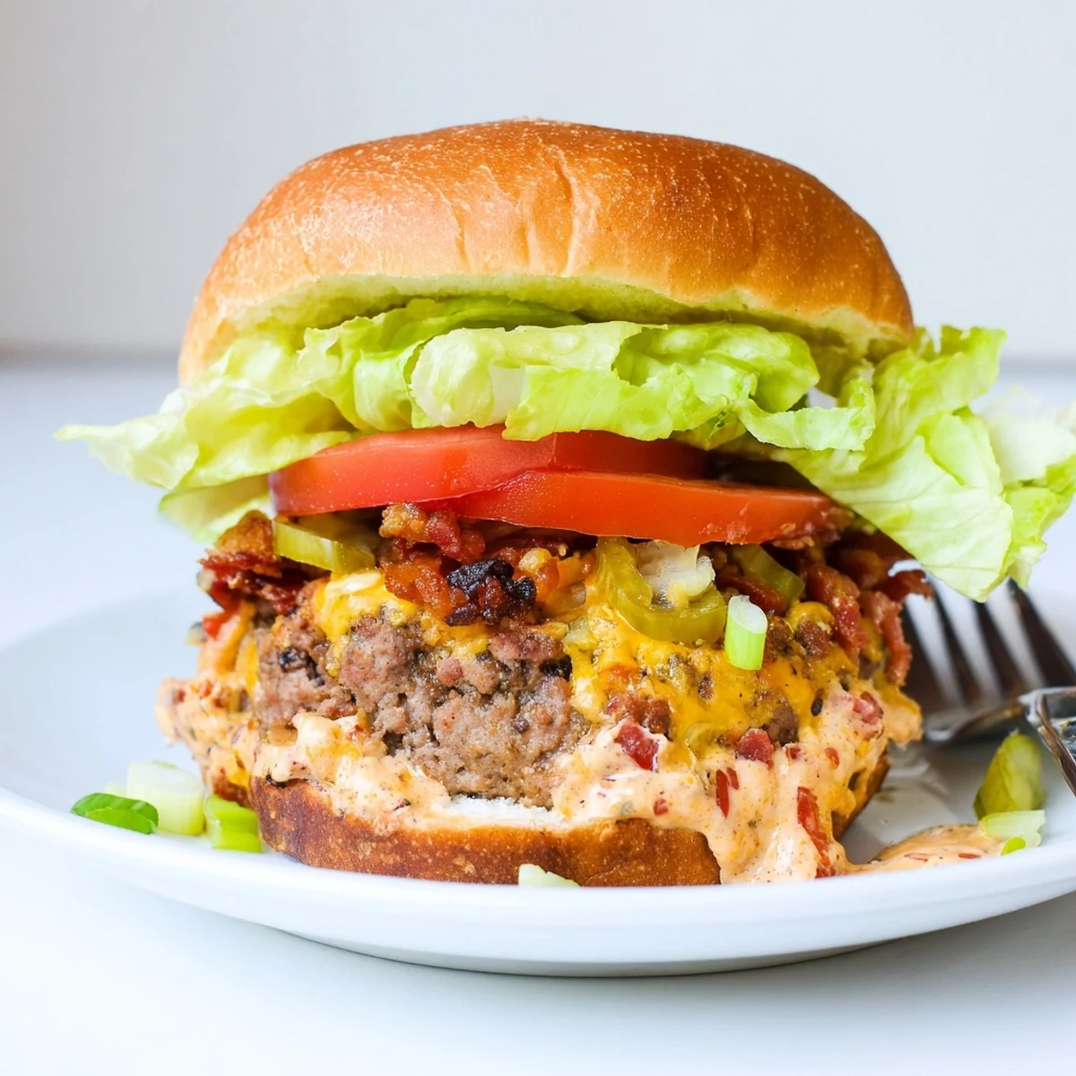 Close-up shows Irresistible Crack Burgers with melted cream cheese topping, tomato slice