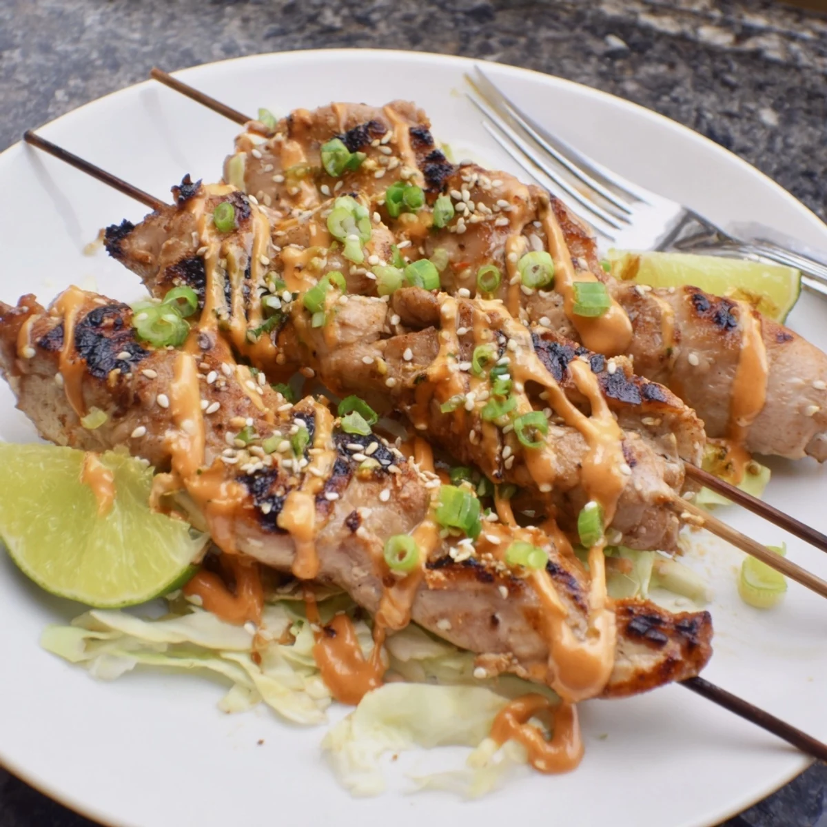 Charred Bang Bang Chicken Skewers on a platter, cilantro and sticky glaze